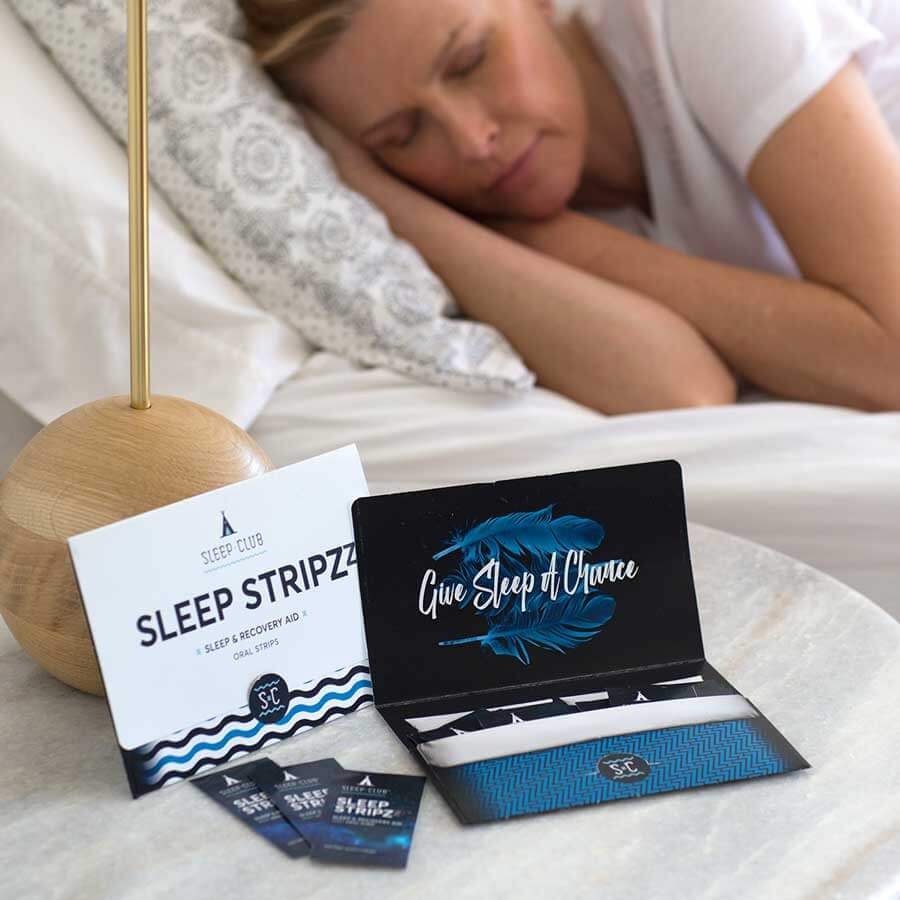An open package of Sleep Stripzzz sleep aid on nightstand. Lady sleeping on bed in background.